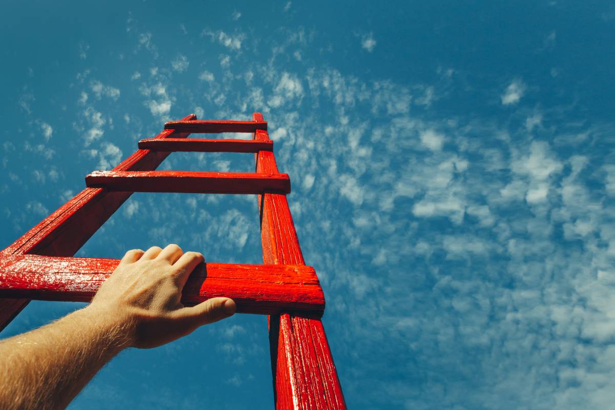 Man's hand reaching for a ladder leading to a blue sky.Development Attainment Motivation Career Growth Concept.